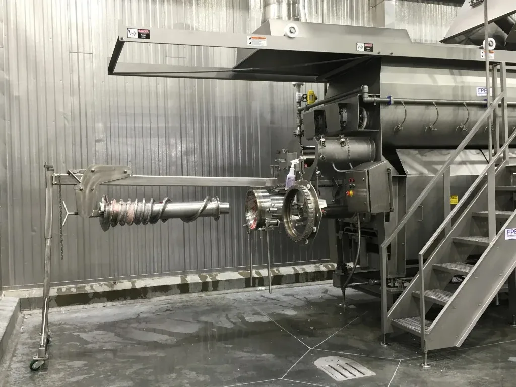 Stainless steel industrial extruder with auger removed for maintenance in a washdown facility
